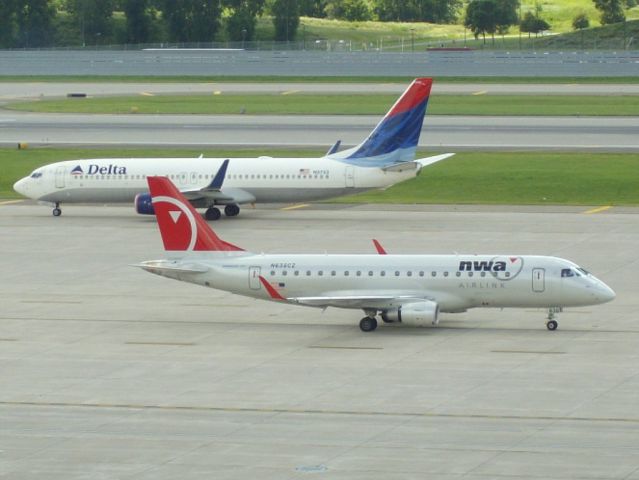 Embraer 170/175 (N638CZ) - A Delta 737 passes a Delta E170 still in Northwest paint at Minneapolis,MN on 7-24-10.