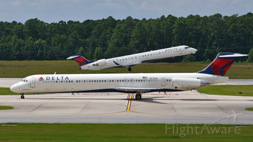 McDonnell Douglas MD-88 (N915DE) - Delta Airlines McDonnell Douglas MD-88 (N915DE) taxis to the gate after arriving at KRDU while in the background Endeavor Air (Delta Connection) Bombardier CRJ-900 (N905XJ) departs KRDU Rwy 5L on 7/29/2017 at 3:21 pm.