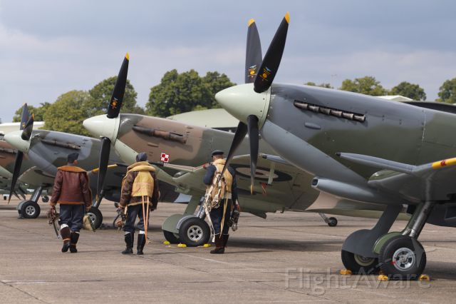 — — - A line up of Supermarine Spitfires, with pilots wearing uniforms from the period.