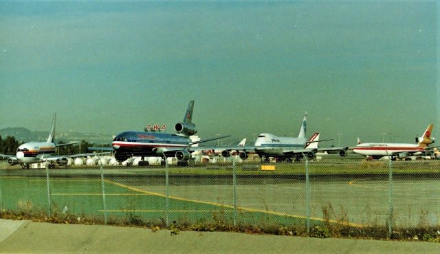 Boeing 737-200 — - KSFO date apprx 1987-88 shows how much fun the SFO Millbrae Ave Airpark was - While Gman was in Loring AFB I was at SFO - I used to call this the "Merry go round: as from about 08:30AM till about 11:00AM this line of jets would never end when departures were off the 1LR Runways and usually a Saturday morning. All types of jets and props would use 1R from EMB-110s to 747s and a mix of many airlines. This photo shows an ex Air Cal Boeing 737-2 in American lettering, leading an AA DC-10-30, Pan Am Clipper Water Witch ( in which I have photos of the PA 747 elsewhere here on FA) and followed by a Continental DC-10. Behind Pan Am is an Air America L-1011 parked at a remote SFO spot. I also filmed a lot of video from here atop the ladder, Ive posted many on my YT page under my screen name MarsAveSo.