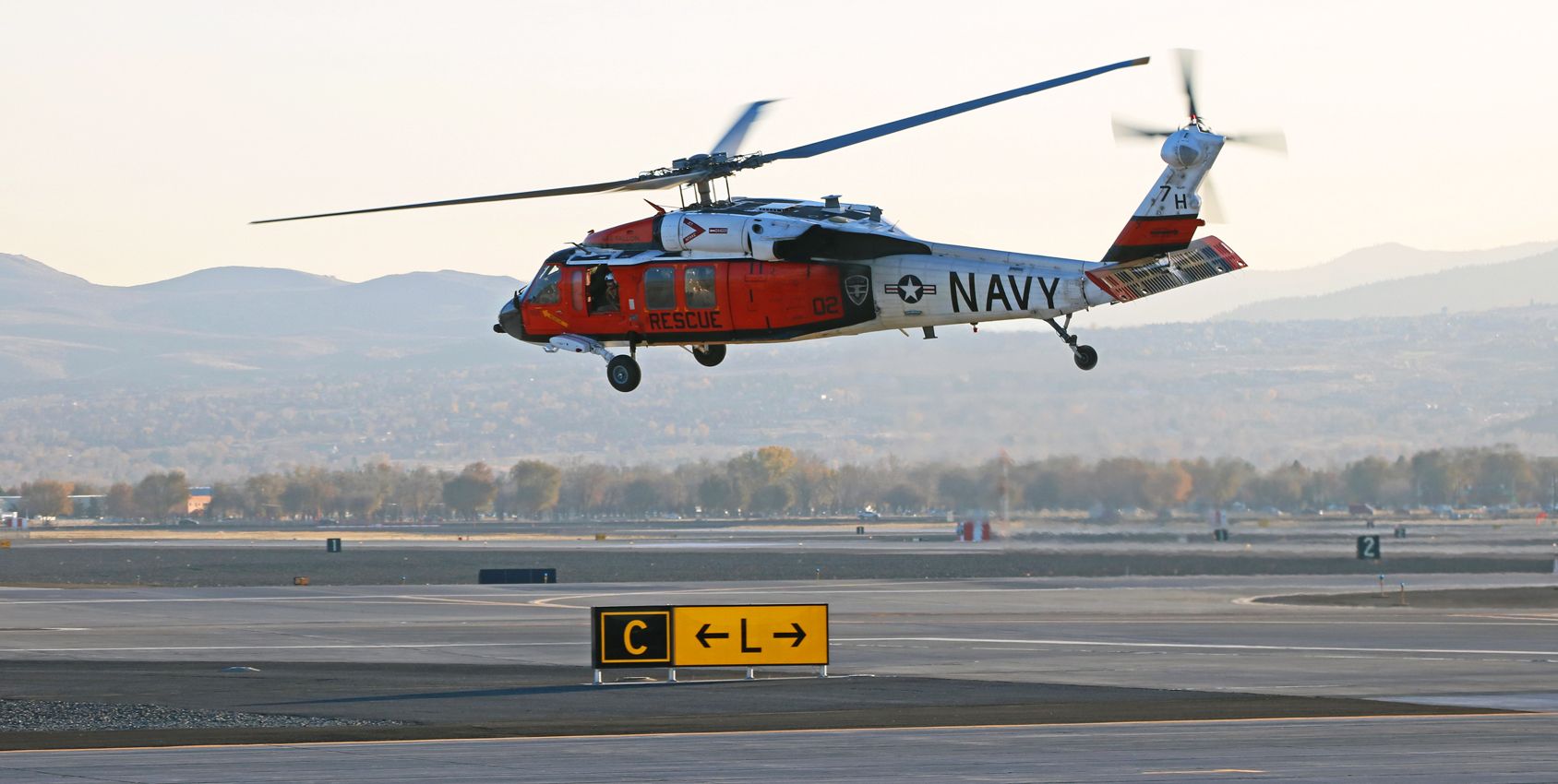 Sikorsky S-70 (16-5760) - The long shadow on the ground next to the taxiway sign gives a good indication of the time of day as Longhorn Oh Two (US Navy "Longhorns" Search and Rescue Team) lifts away from Lima during the sunset hour and begins turning east to make a short return trip to NAS Fallon.