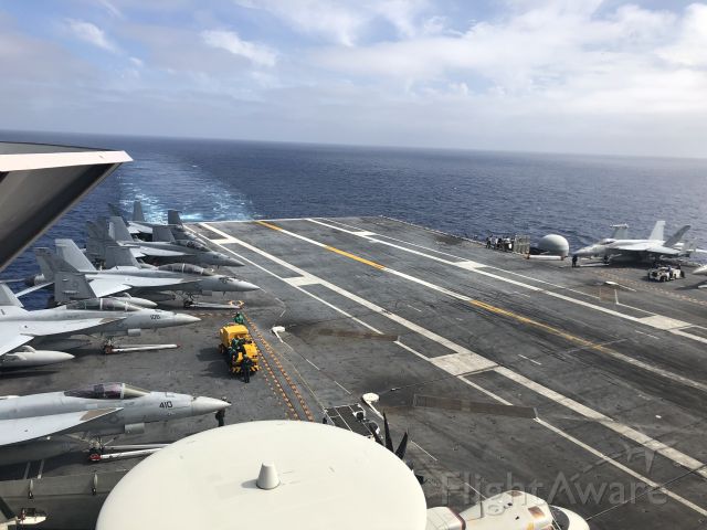Grumman E-2 Hawkeye — - The crew of the U.S.S. John C. Stennis (CVN-74) and the Landing Signal Officers of Carrier Air Wing Nine (CVW-9) prepare to recover aircraft during cyclic ops on Saturday, April 21, 2018.  In the foreground, the top of an E-2C Hawkeye from VAW-117 "Wallbangers" sits parked, along with a F/A-18E from VFA-151 "Vigilantes."  Aft of the Vigilantes bird are three F/A-18F Super Hornets from VFA-41 "Black Aces."  The final jet on the left hand side is a F/A-18E from VFA-14 "Tophatters."  I took this picture from "Vultures Row," which offered an incredible view of flight operations.
