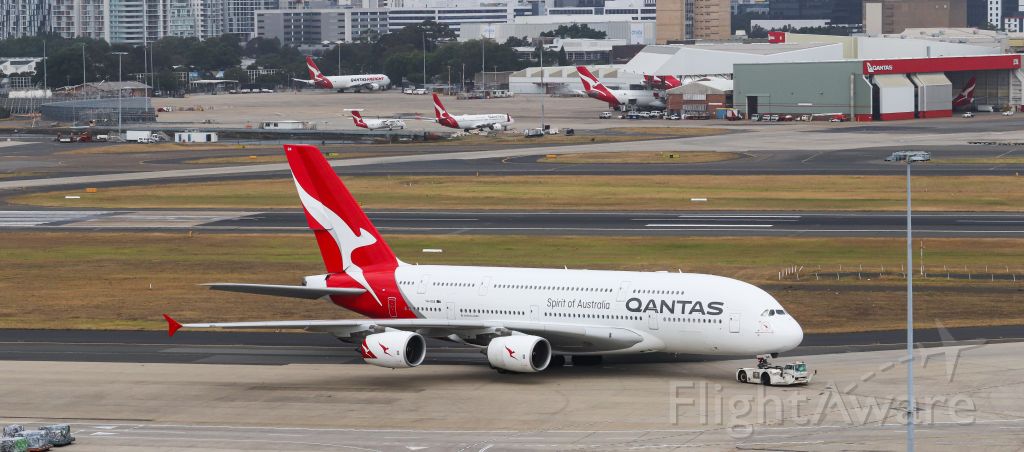 Airbus A380-800 (VH-OQA) - QANTAS A380 being towed to the gate with multiple aircraft of the QANTAS fleet in the background.