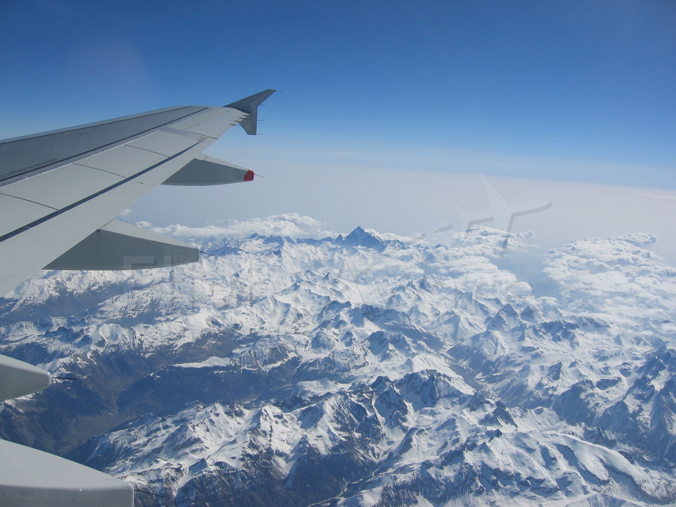 — — - View of wing over French Alps on flight from Nice to London