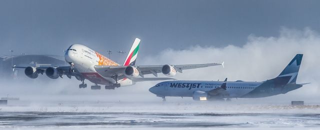 Boeing 737 MAX 8 (C-FNWD) - This Westjet Max8 holds short of the active as an Emirates A380 in the gold Expo 2020 (A6-EOE) livery gets airborne off runway 33R at YYZ kicking up a huge snow cloud behind her!