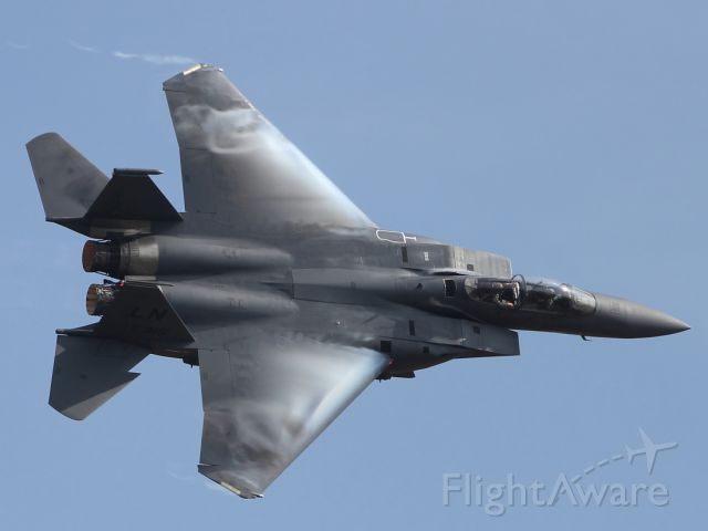 — — - Condensation forms above the wing of this F-15 Eagle as it performs a high speed fly past at Duxford Air Museum.