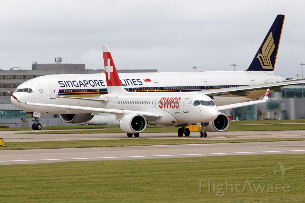 Bombardier CS100 (HB-JBA) - The CS100 looking very small with a B77W lurking behind, SWR391 waits to be cleared to line up for the flight back to Zurich