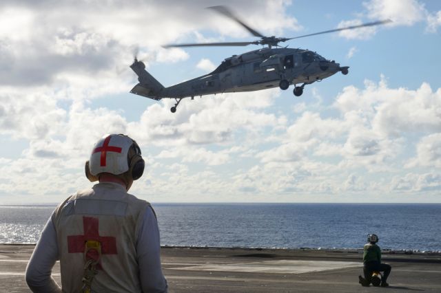 — — - A U.S. sailor waits as a MH-60S Seahawk helicopter assigned to Helicopter Sea Combat Squadron 15 lands on the flight deck of the aircraft carrier USS Carl Vinson in the Pacific Ocean, May 31, 2015.
