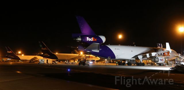 Boeing MD-11 (N601FE) - Fed Exs N601FE, named "Jim Riedmeye," is brilliantly illuminated by portable spotlights so holiday-season cargo can be unloaded after the MD-11 arrived at Reno from Memphis.  In the background, two B757s (from left ... N780FD "Harvey" and N966FD "Kiana") have already been partially loaded with holiday mail destined for the east coast.  All three FDX fleetbirds departed for Memphis a couple of hours after I clicked this shot from my position on Alpha taxiway.br /N601FE was one of three heavies to land back-to-back at RTIA.  Two UPS bigbirds had touched down just prior to "Jim Riedmeyes" arrival; a Boeing 763 and an Airbus 306.  All total, there were six cargo aircraft on the ramp when I was out there.  I did not stay out very long; the temp was down in the teens so it was dang chilly, but I was out there long enough to get some excellent snaps.  