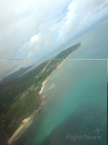— — - Still in the Twin Otter as she turns slightly to approach the airfield located on Praslin island in the Seychelles just beyond and in the background.
