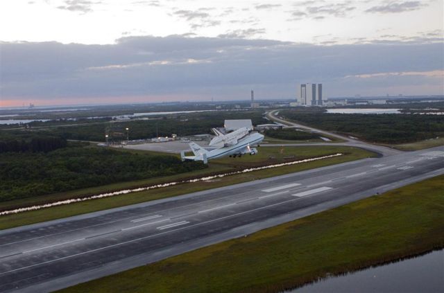 Boeing Shuttle Carrier (NASA905) - Climbing out of the SLF (KTTS) with the VAB in the background.