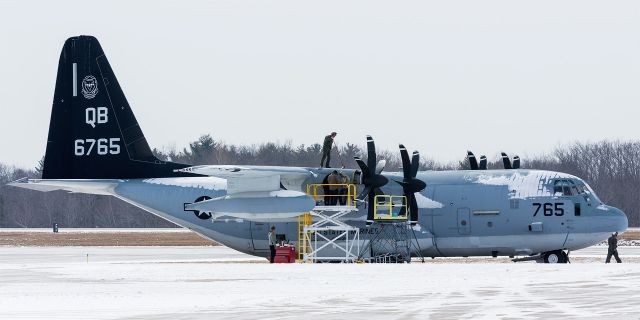 Lockheed C-130 Hercules (16-6765) - long way from Cali... a flight crew member sweeps off snow as the work on the engine 