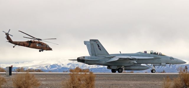 McDonnell Douglas FA-18 Hornet (16-5805) - A Hawk and a Hornet ..... A NAWDC F/A-18F (165805) rolls south on KNFLs taxiway Alpha for a launch from runway 31L as, in the background, a Sikorsky MH-60s Knighthawk (167838, an S-70), lifts away. Both aircraft were departing to participate in a morning training exercise with an F/A-18 Growler squadron from Australia (6 Squadron, RAAF Base Amberley).br /** NAWDC was formerly NSAWC.  The title on the tail of this Super Bug has not yet been repainted. **