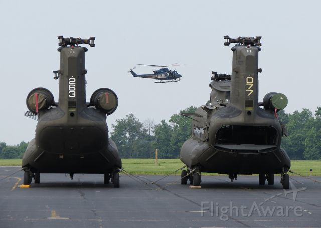 — — - Two Boeing CH-47 Chinooks waiting modifications while a Delaware State Trooper Bell 407 goes through maneuvers.